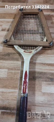 Това е дървена тенис ракета Slazenger от миналия век, поставена в трапецовидна дървена преса.
