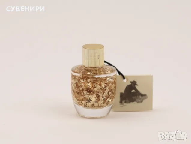 Малка бутилка, пълна със златни люспи варак.Символика: Златото отдавна се свързва с богатство, успех